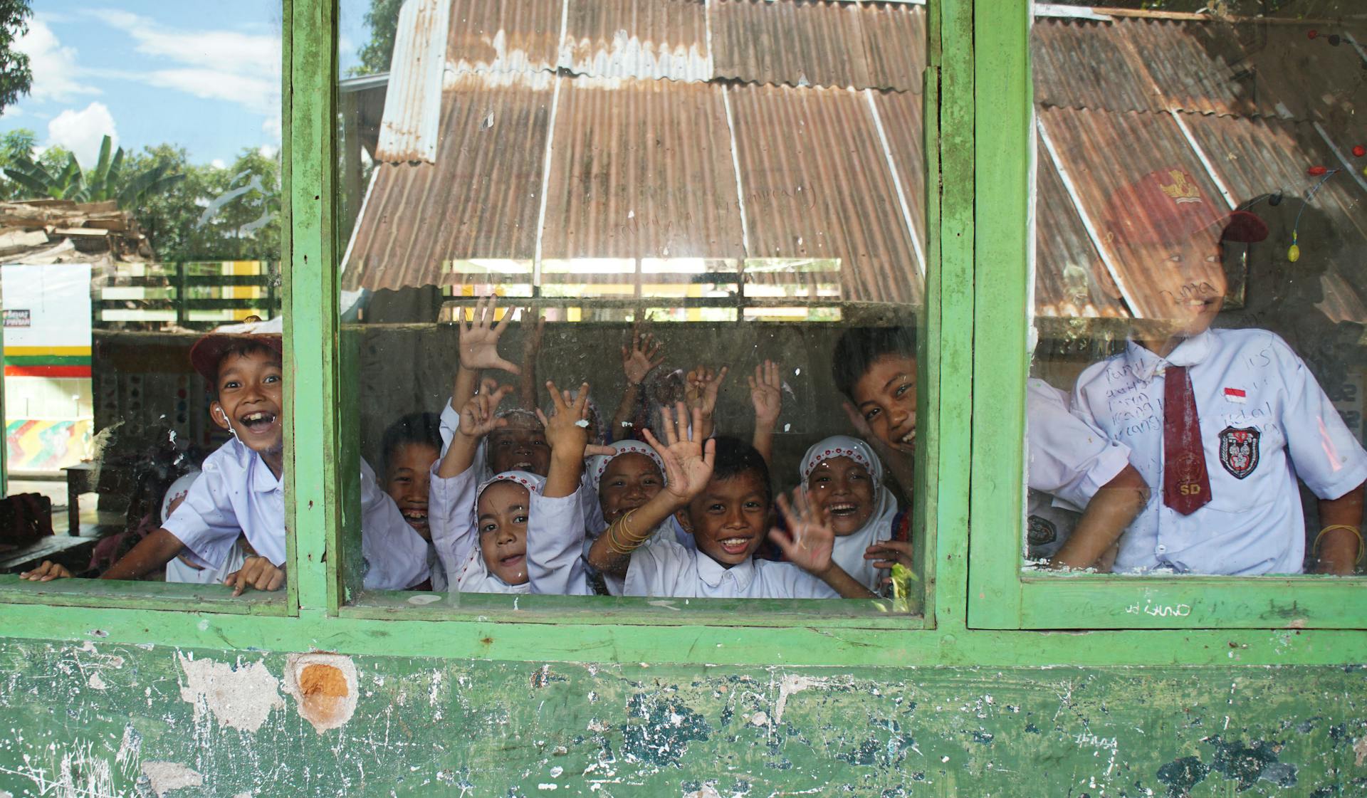 Schoolchildren waving from inside a simple village schoolhouse