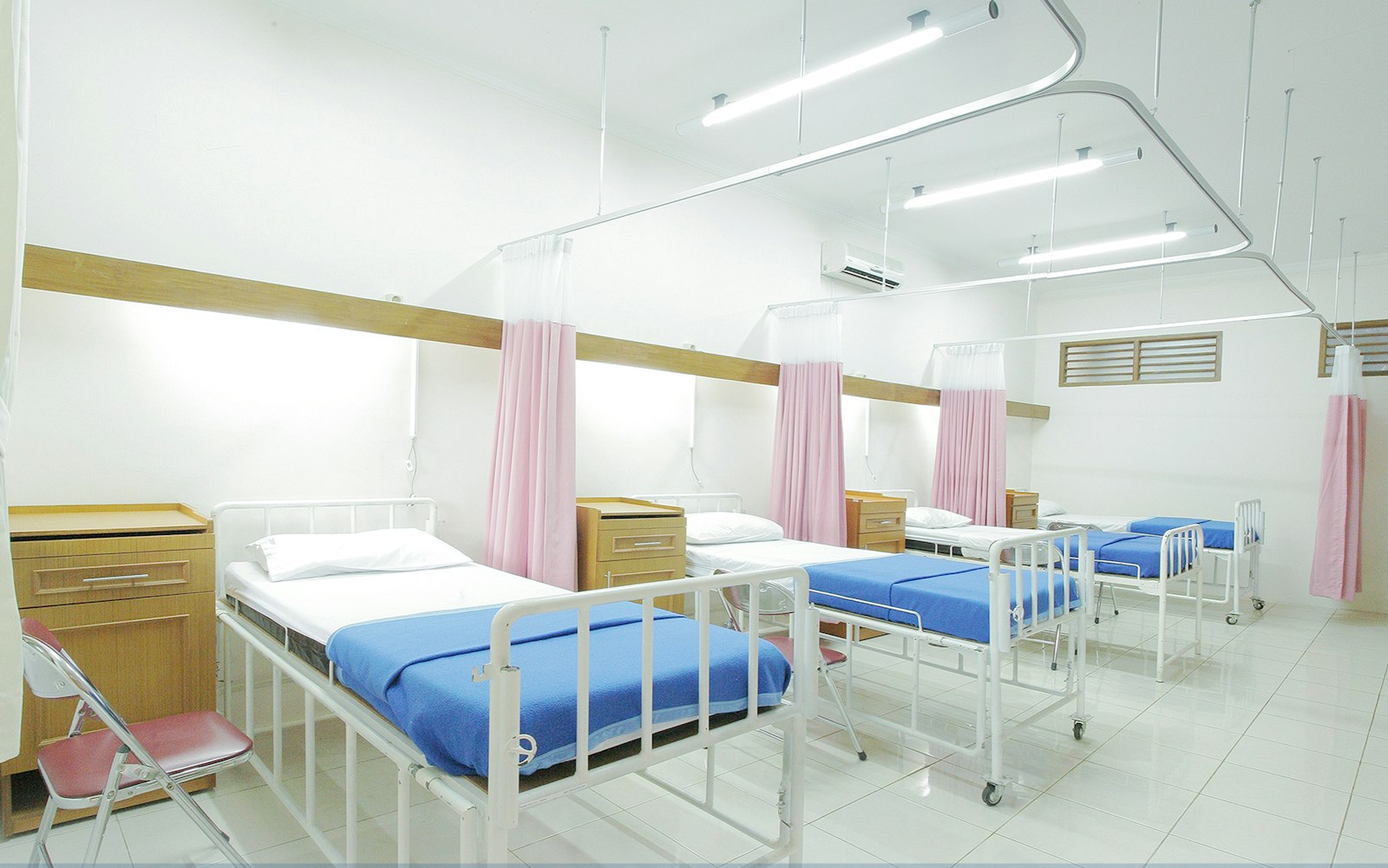 An empty hospital ward, beds prepared and waiting