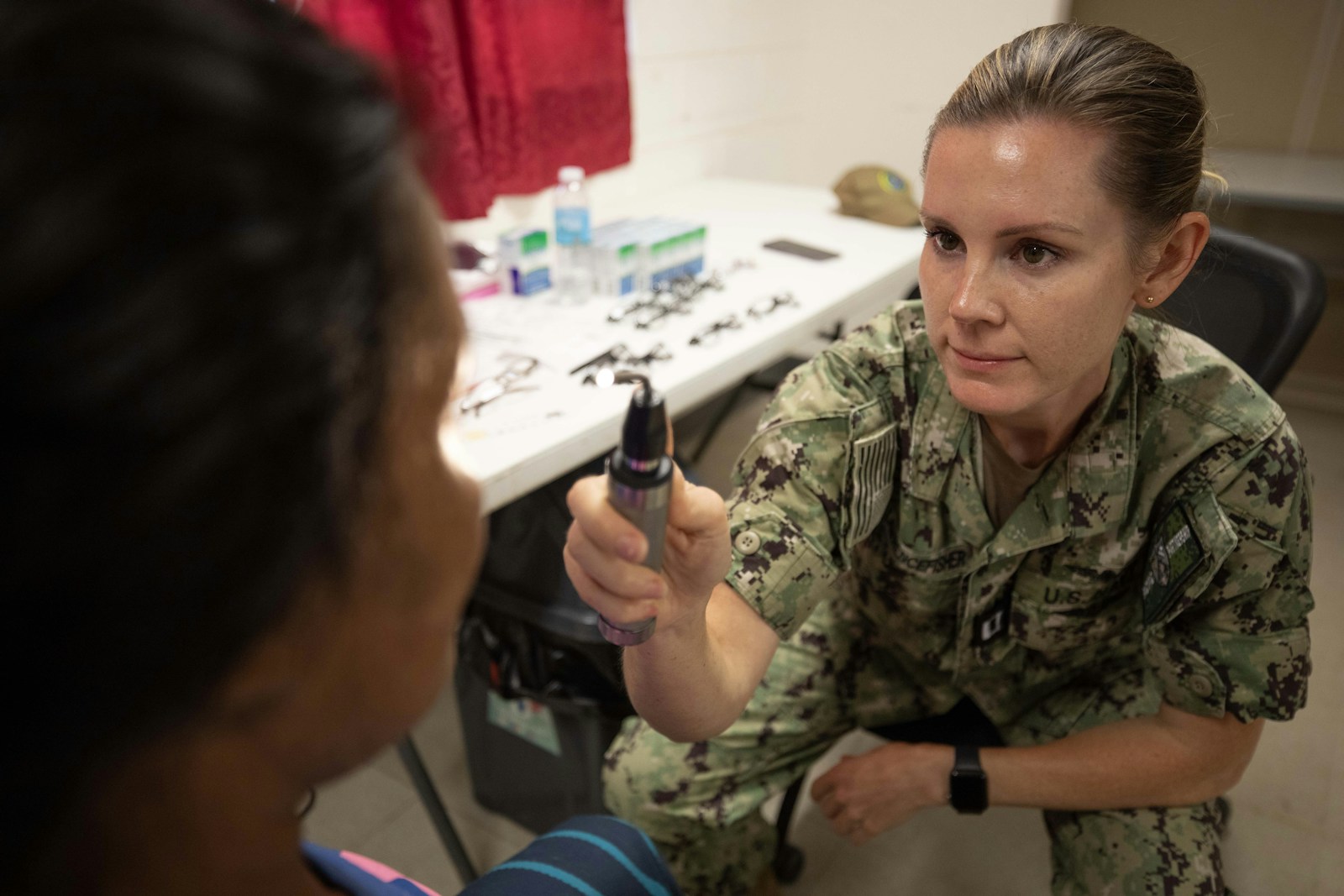 A volunteer medic conducting a field eye exam on a patient at a humanitarian clinic